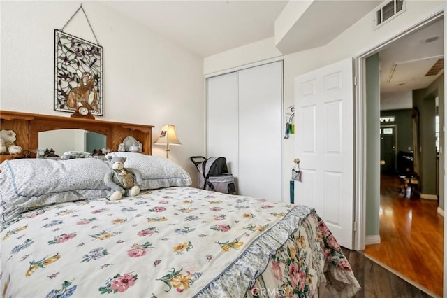 bedroom with dark wood finished floors, baseboards, visible vents, and a closet