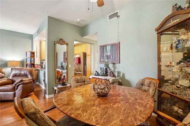 dining room featuring light wood-type flooring, visible vents, baseboards, and a ceiling fan