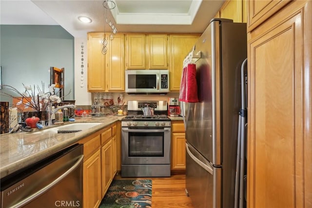 kitchen featuring light wood finished floors, recessed lighting, a sink, stainless steel appliances, and light countertops