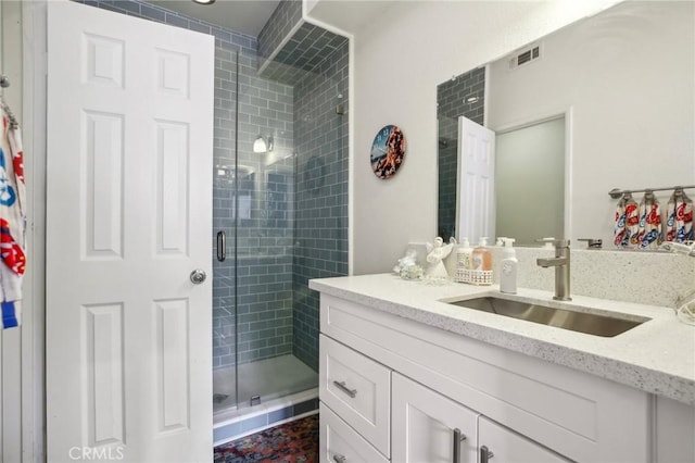 bathroom featuring visible vents, a stall shower, and vanity