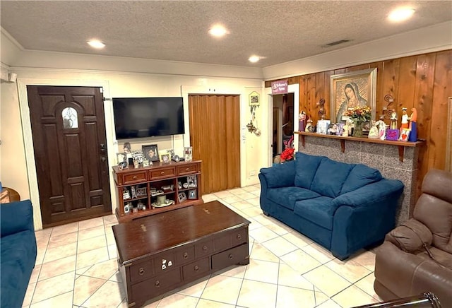 living area featuring wooden walls, visible vents, recessed lighting, tile patterned flooring, and a textured ceiling