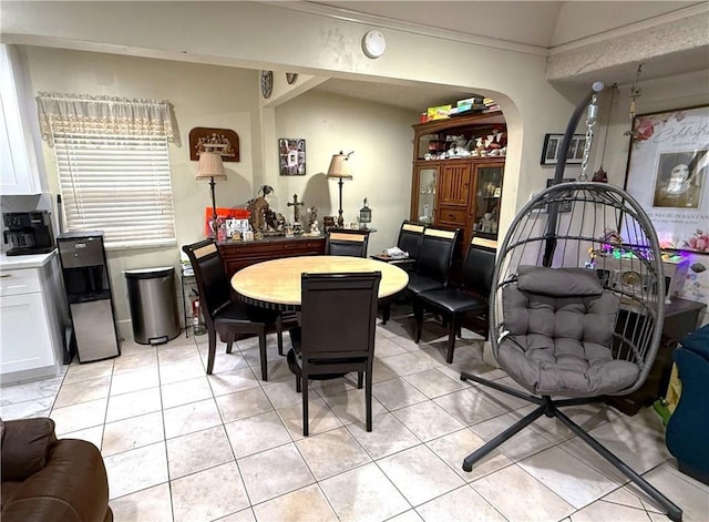 dining area with arched walkways and light tile patterned flooring