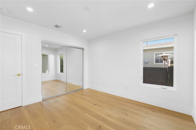 unfurnished bedroom with recessed lighting, visible vents, light wood-style flooring, and a closet