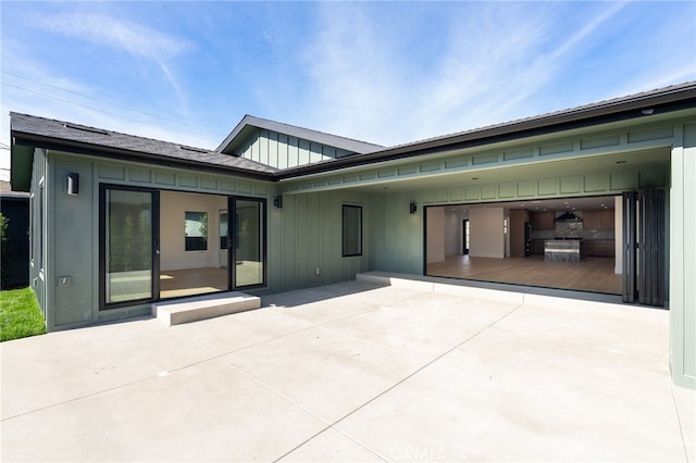 back of house with a patio, an attached carport, board and batten siding, and driveway