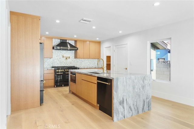 kitchen featuring range with two ovens, light wood-style flooring, a sink, dishwasher, and wall chimney exhaust hood