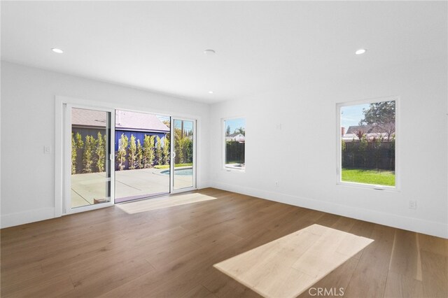 empty room featuring recessed lighting, baseboards, and wood finished floors