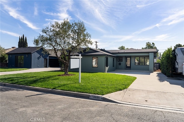 view of front of property featuring a garage, concrete driveway, and a front lawn