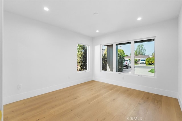 empty room featuring baseboards, plenty of natural light, and light wood finished floors