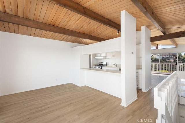 interior space featuring beam ceiling, wooden ceiling, light wood-type flooring, and a sink