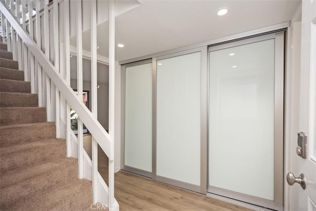 stairway with wood finished floors and recessed lighting