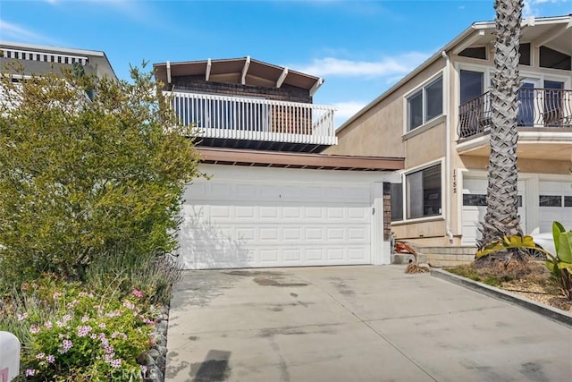 view of front of house with concrete driveway, a balcony, an attached garage, and stucco siding