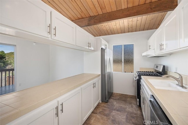 kitchen featuring under cabinet range hood, tile countertops, appliances with stainless steel finishes, and white cabinetry