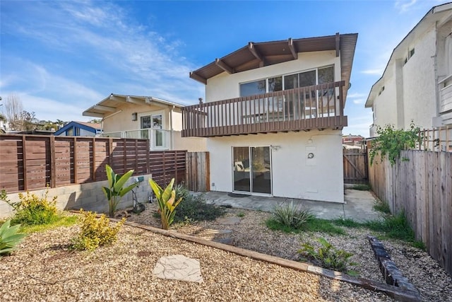 rear view of house with stucco siding and a fenced backyard