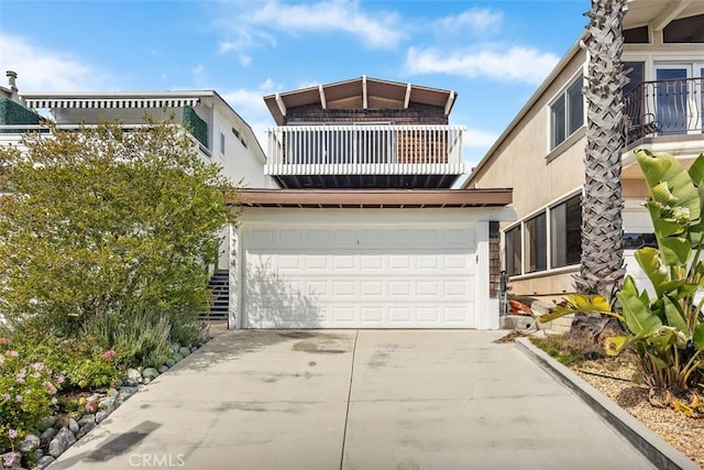 view of front of home featuring an attached garage, driveway, and a balcony