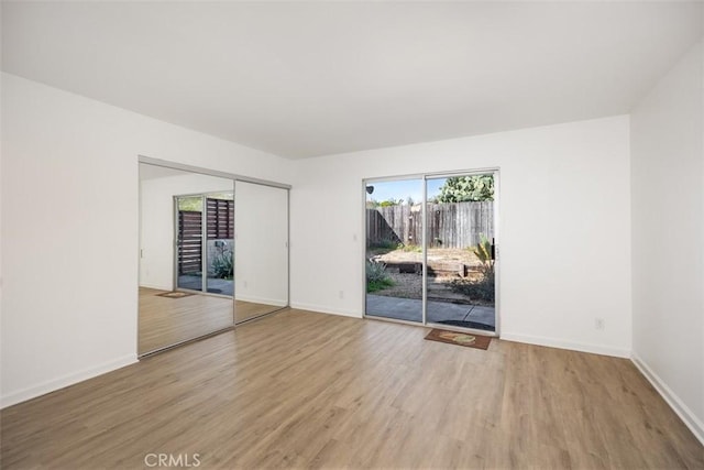 spare room with baseboards and wood finished floors