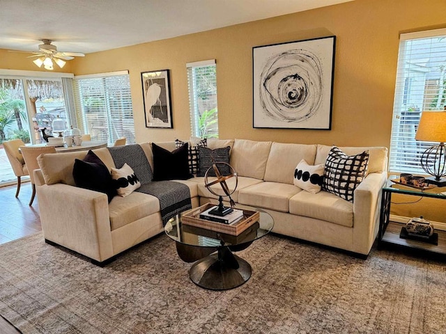 living area with a ceiling fan, plenty of natural light, and wood finished floors