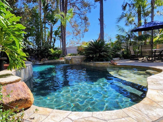 view of swimming pool with a patio area, a pool with connected hot tub, and fence