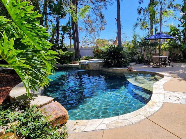 view of swimming pool with a patio area, a pool with connected hot tub, and a fenced backyard