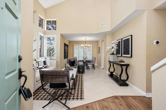 entrance foyer with visible vents, high vaulted ceiling, light wood finished floors, baseboards, and a chandelier