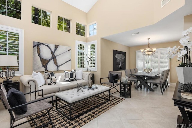 living room featuring light tile patterned flooring, visible vents, a towering ceiling, and a chandelier