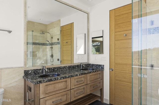 bathroom featuring a sink, toilet, a stall shower, and double vanity