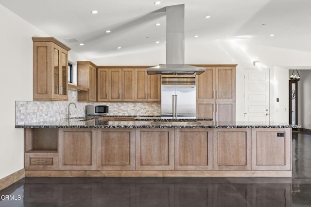 kitchen with island exhaust hood, dark stone countertops, appliances with stainless steel finishes, decorative backsplash, and lofted ceiling