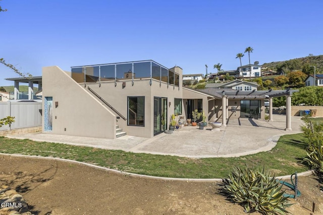 rear view of house featuring stucco siding, a patio, and fence