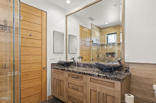 bathroom with a sink, visible vents, a stall shower, and double vanity