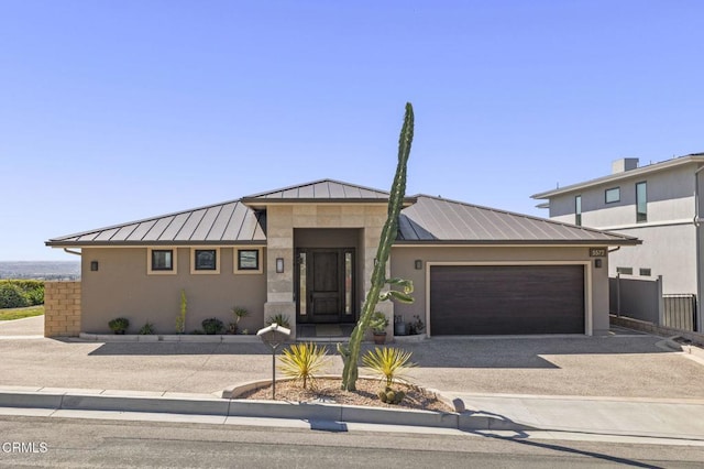 view of front of home with metal roof, driveway, stucco siding, and a standing seam roof