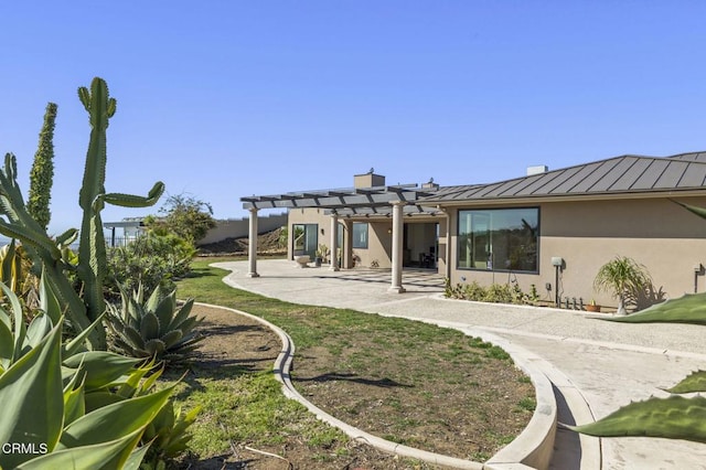 back of house featuring stucco siding, metal roof, a patio area, a pergola, and a standing seam roof