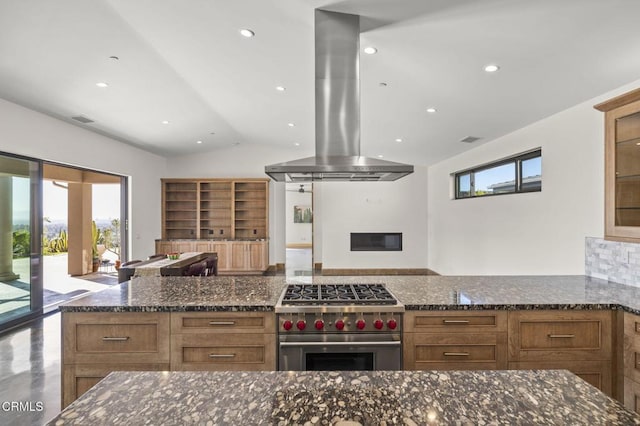 kitchen with stainless steel stove, dark stone countertops, open floor plan, and island range hood