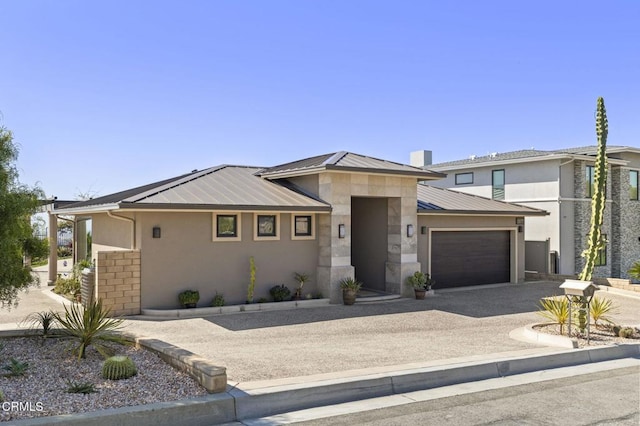 prairie-style house featuring stucco siding, driveway, stone siding, an attached garage, and metal roof