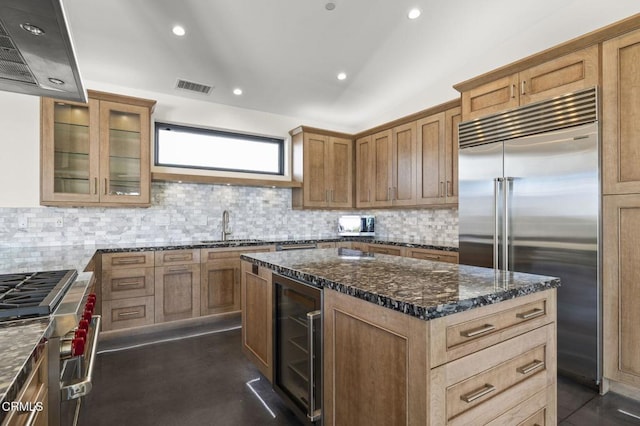 kitchen featuring high end appliances, beverage cooler, visible vents, dark stone counters, and a sink