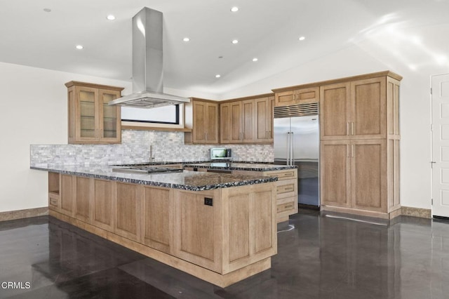 kitchen with tasteful backsplash, glass insert cabinets, dark stone countertops, island range hood, and stainless steel appliances