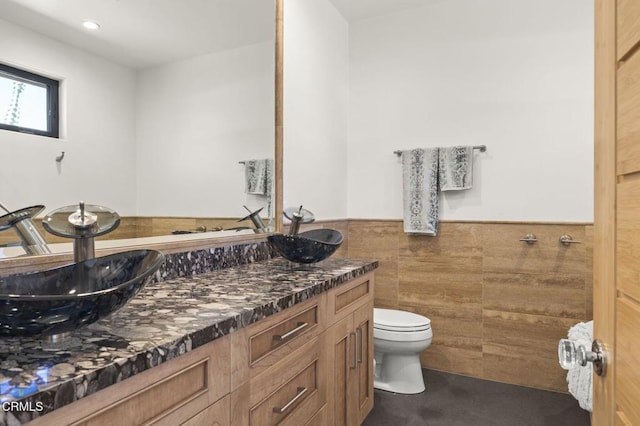 bathroom with vanity, recessed lighting, wainscoting, tile walls, and toilet