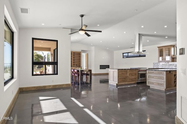 kitchen featuring a ceiling fan, recessed lighting, island exhaust hood, stainless steel stove, and vaulted ceiling