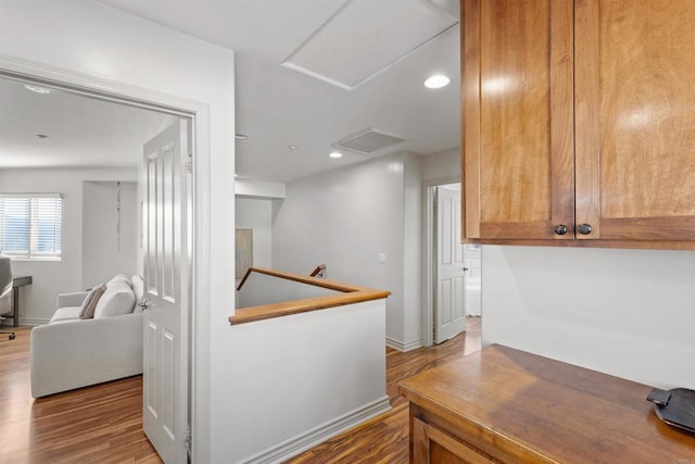 hall with visible vents, attic access, an upstairs landing, recessed lighting, and wood finished floors