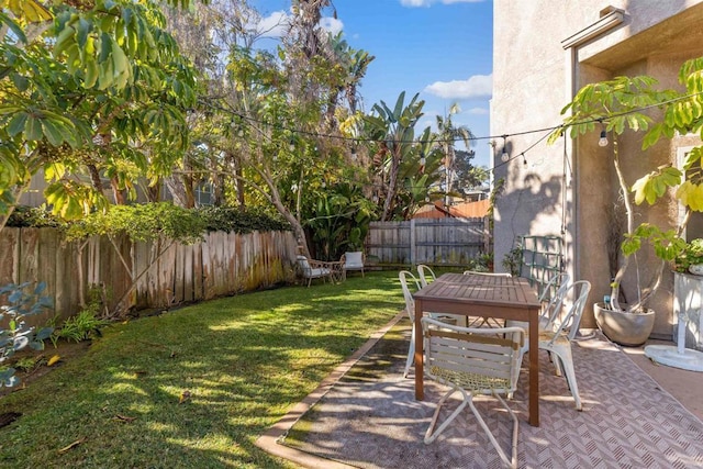 view of yard featuring outdoor dining space, a patio area, and a fenced backyard