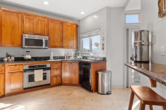 kitchen featuring light tile patterned floors, recessed lighting, brown cabinets, black appliances, and a sink