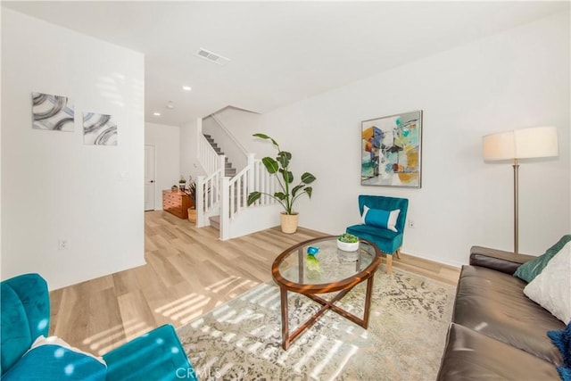 living room with stairway, visible vents, and wood finished floors