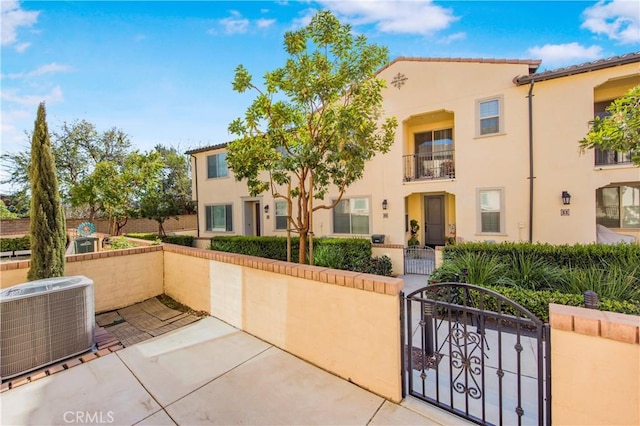 exterior space with central air condition unit, a fenced front yard, stucco siding, and a gate