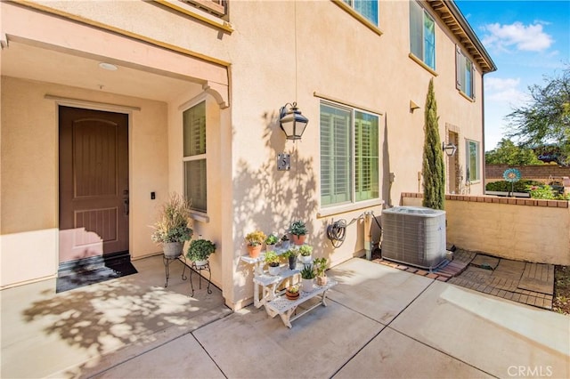 entrance to property featuring central air condition unit, a patio area, and stucco siding