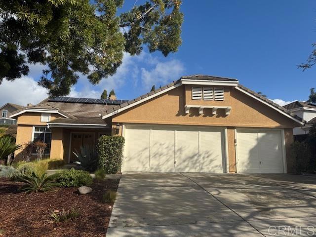 view of front facade featuring stucco siding, an attached garage, concrete driveway, and solar panels