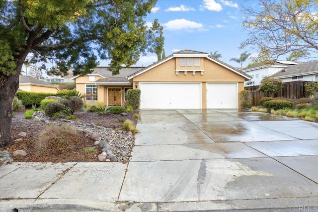 view of front of house with an attached garage, fence, driveway, and stucco siding