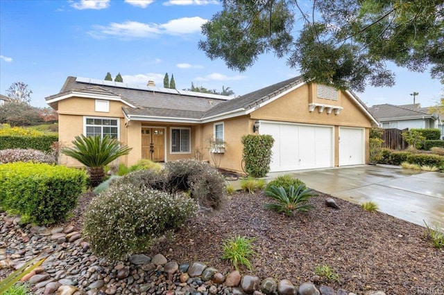 single story home with stucco siding, roof mounted solar panels, concrete driveway, and an attached garage