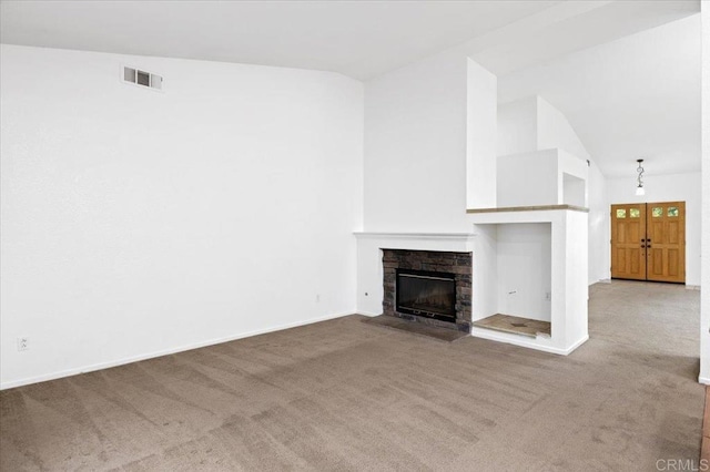 unfurnished living room featuring visible vents, baseboards, lofted ceiling, a fireplace, and carpet flooring