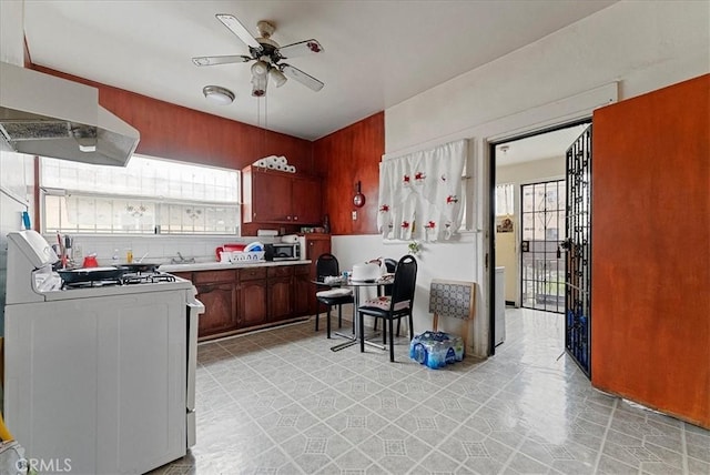 kitchen featuring a healthy amount of sunlight, white gas range, under cabinet range hood, and ceiling fan