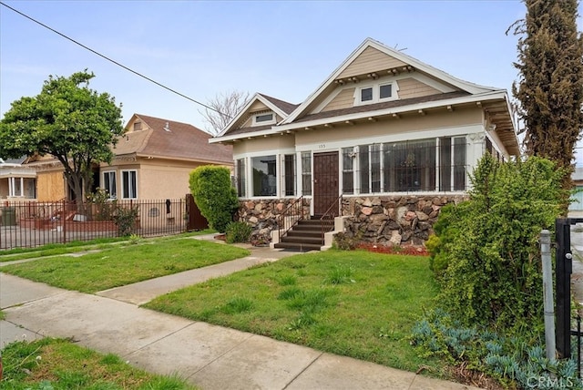 view of front facade featuring stone siding, a front lawn, and fence