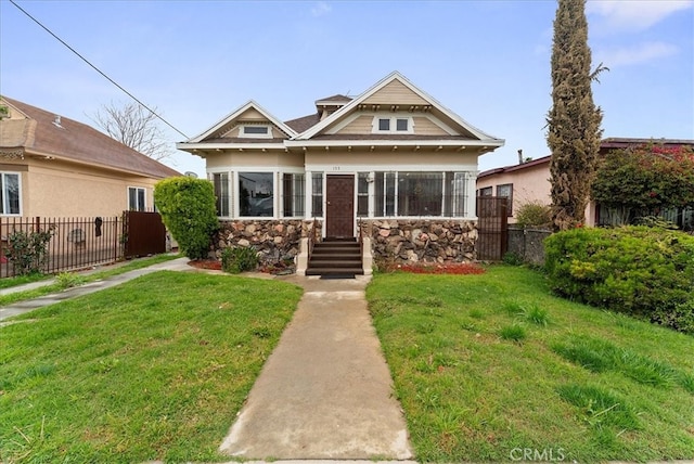 view of front of home featuring stone siding, a front yard, and fence