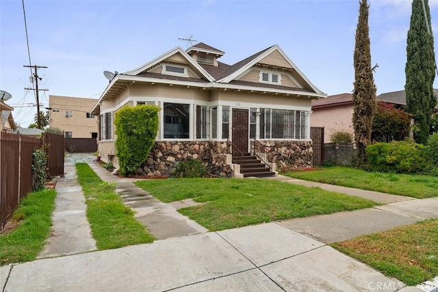 view of front of property with a front yard, fence, and stone siding